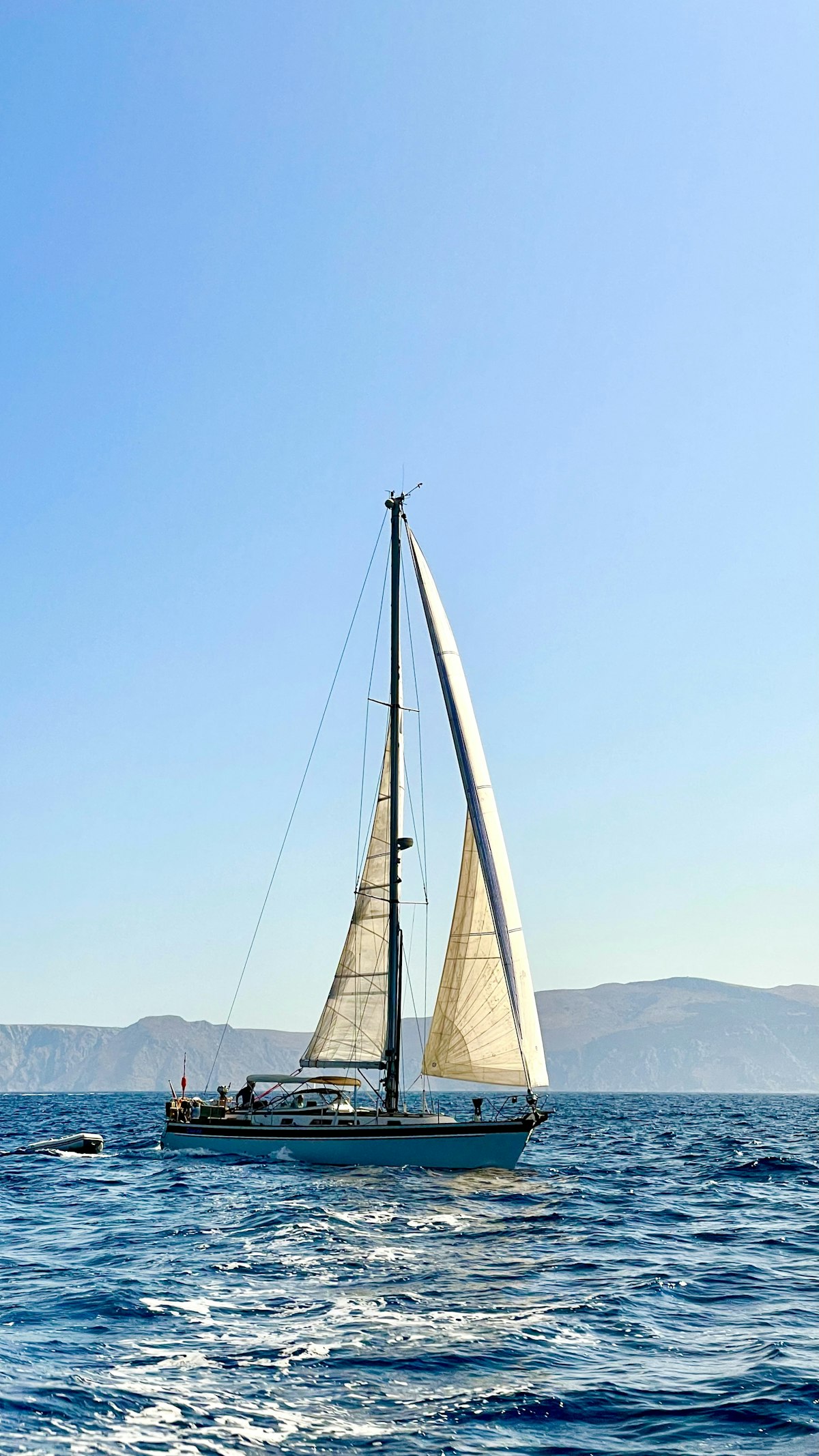 山を背景に航行するセーリングヨット